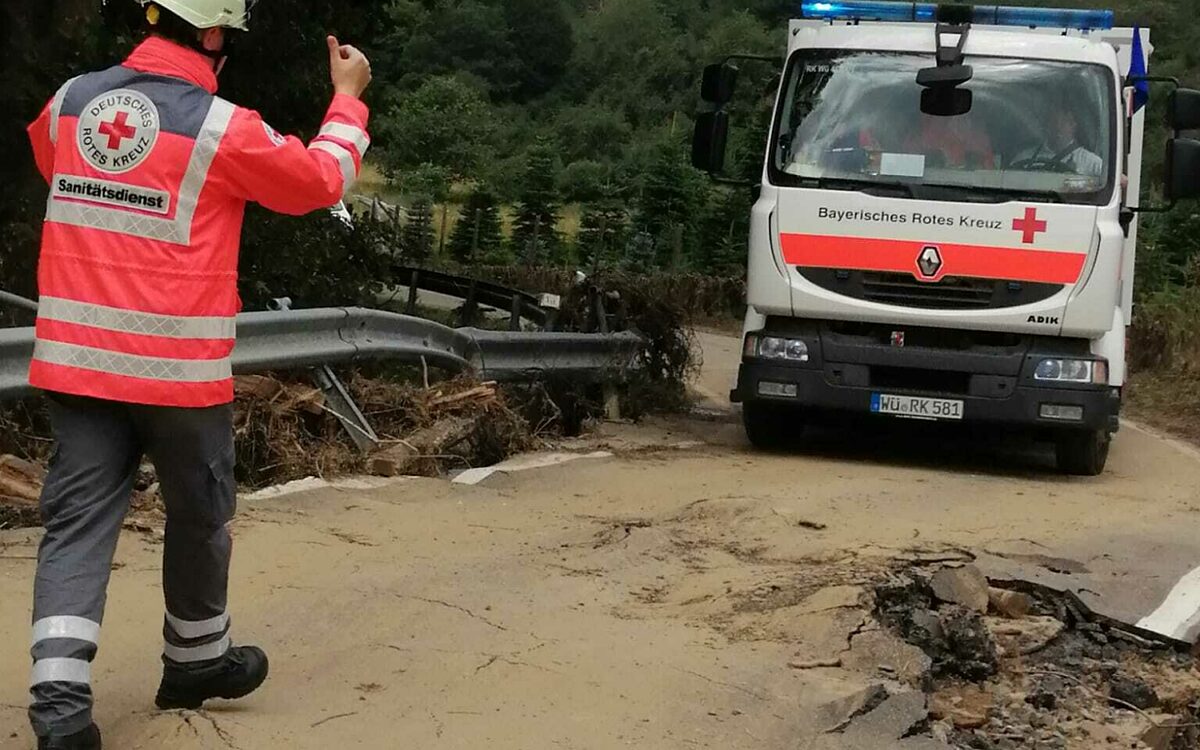 BRK Unterfranken im Hochwassergebiet in Rheinland-Pfalz - ein BRKler lotst ein BRK-Fahrzeug eine schlammige Straße entlang BRK Unterfranken im Hochwassergebiet in Rheinland-Pfalz - ein BRKler lotst ein BRK-Fahrzeug eine schlammige Straße entlang